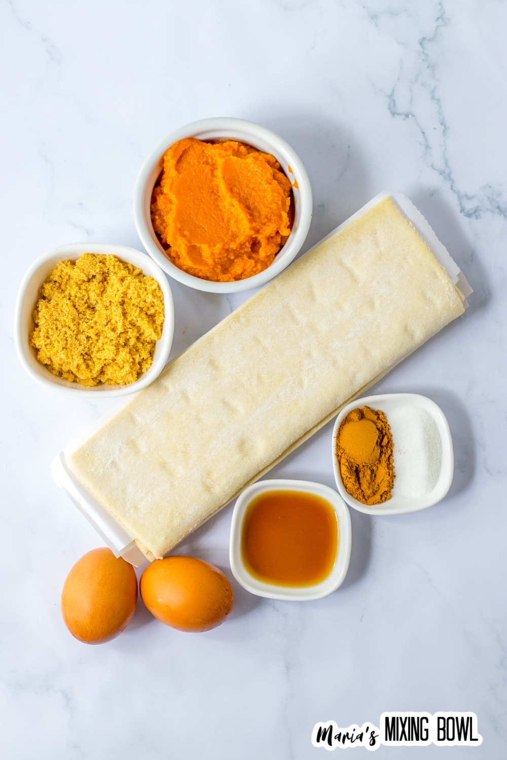 bowls of pumpkin puree, brown sugar, eggs, vanilla, cinnamon, white sugar, and two sheets of puff pastry.