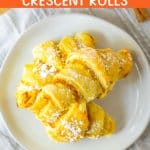 three pumpkin pie crescent rolls stacked on a white plate.