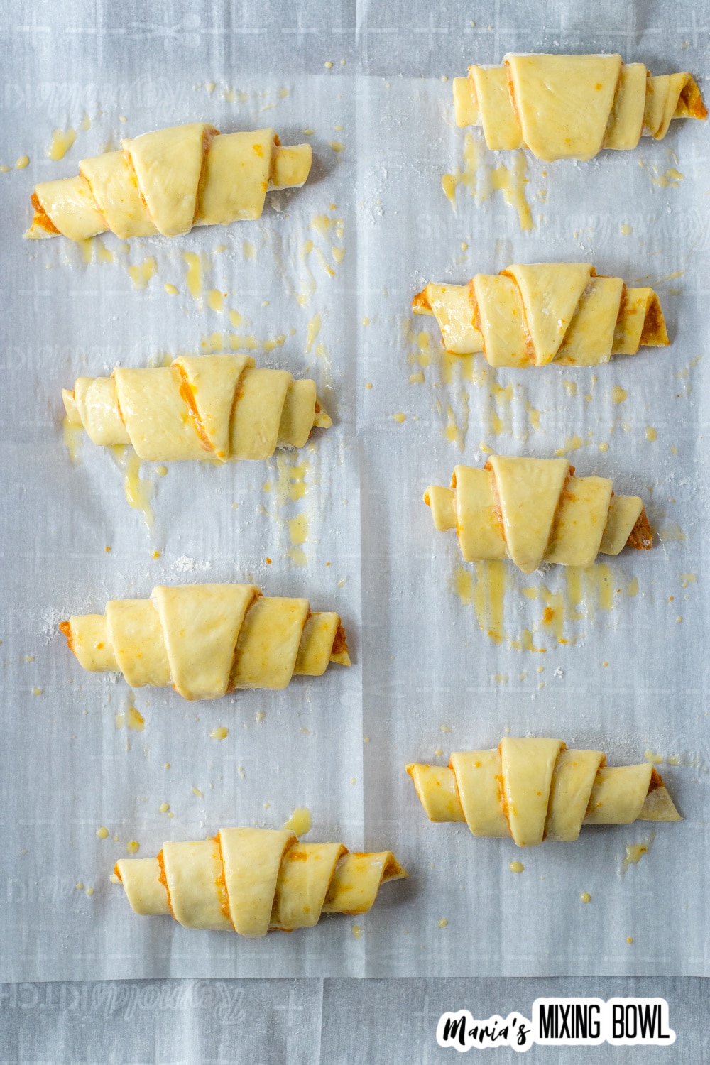unbaked crescent rolls on a parchment lined baking sheet.