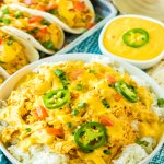 bowl of slow cooker queso chicken over rice and topped with jalapeno slices.