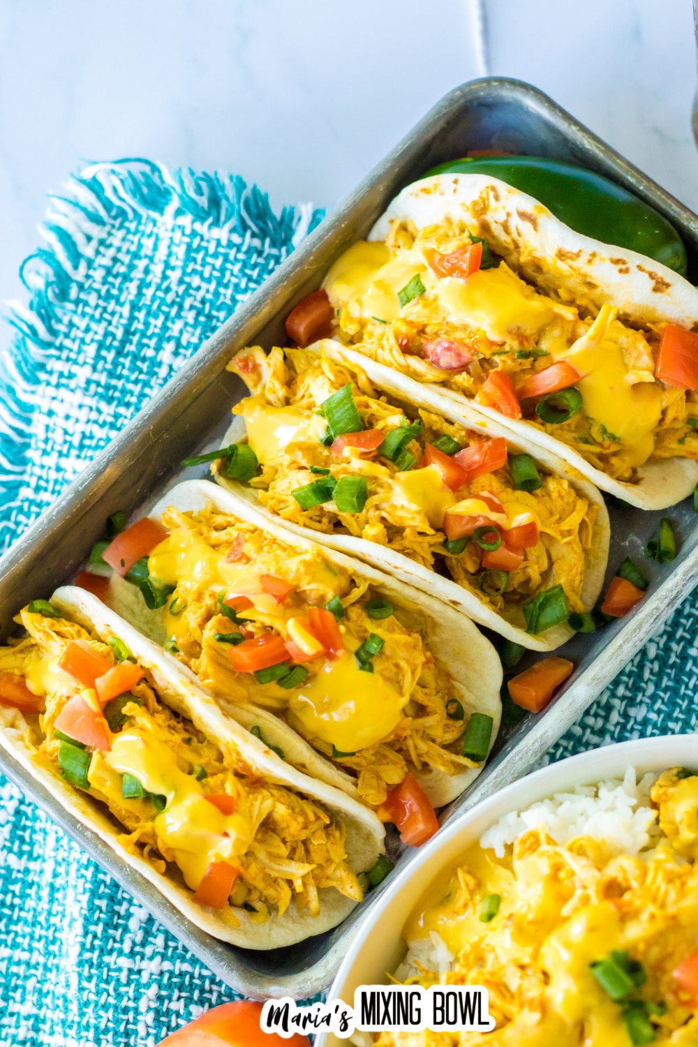 tacos stuffed with queso chicken in a metal tray.