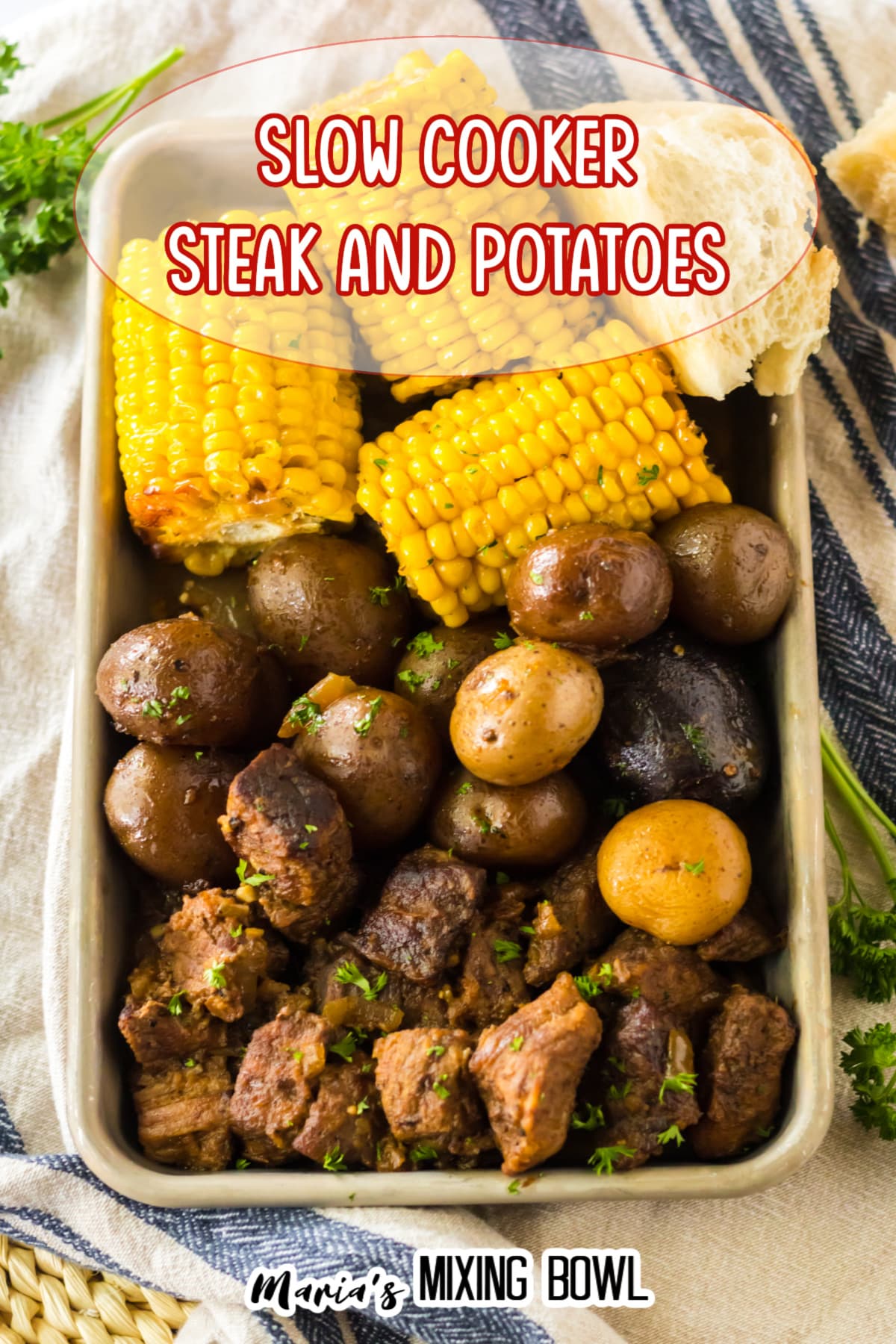 metal tray filled with beef tips, cooked potatoes, and corn on the cob.