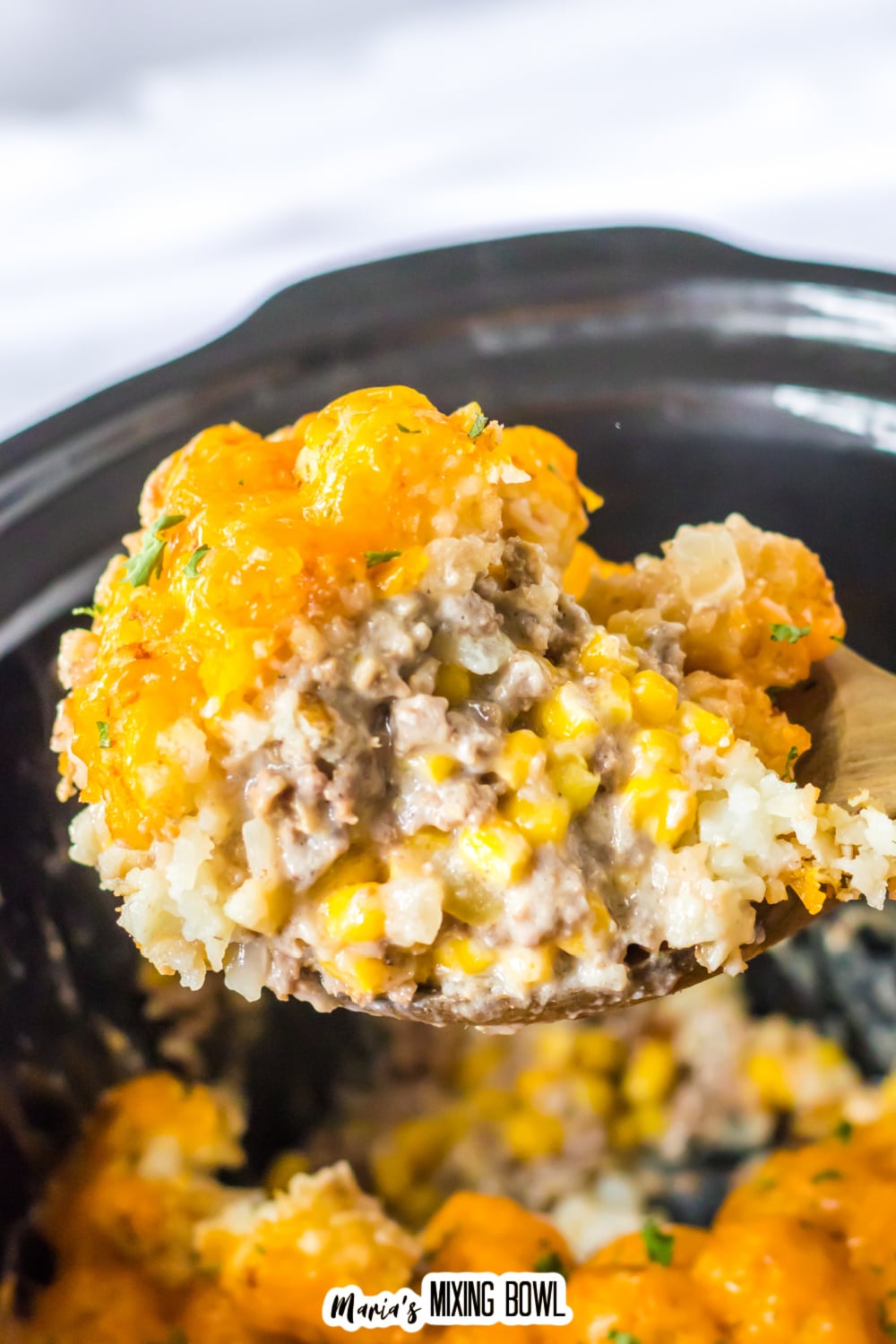 spoonful of slow cooker tater tot casserole held in the air.