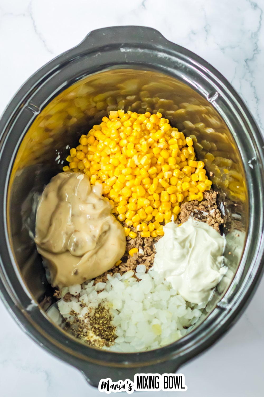 cooked ground beef, corn, onions, seasonings, sour cream, and cream of mushroom soup in a slow cooker.