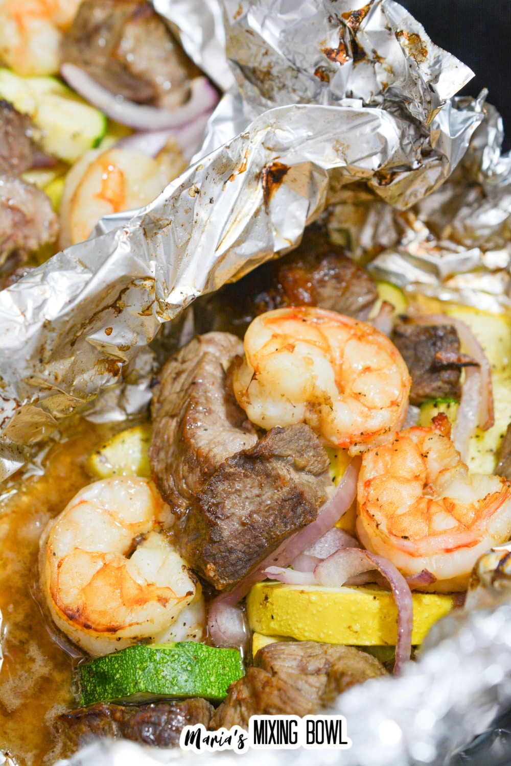 close up of the inside of a foil packet filled with steak and shrimp.