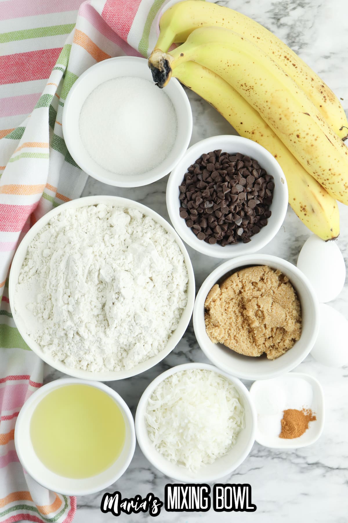 bananas, bowls of flour, sugar, brown sugar, coconut, cinnamon, salt, and oil.