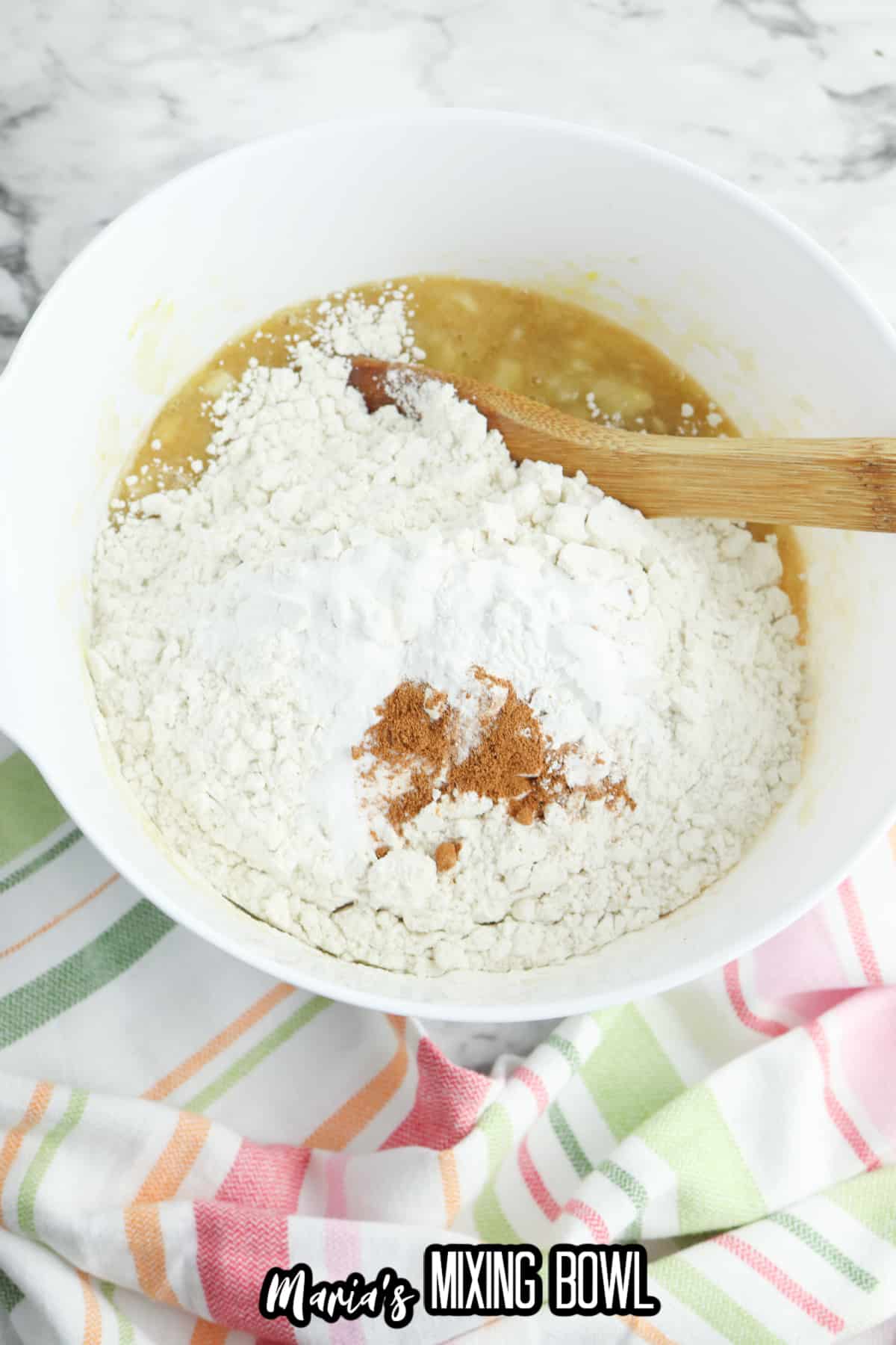 flour, salt, and cinnamon being added to the wet ingredients in a mixing bowl.