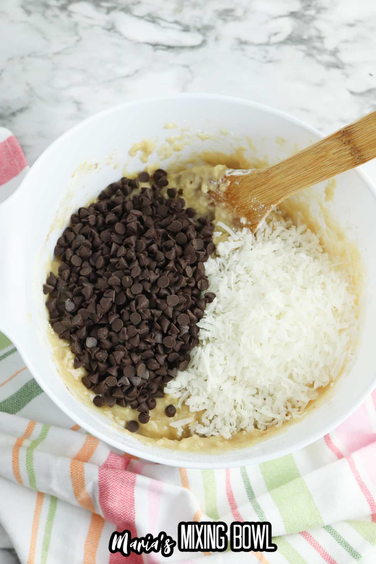 chocolate chips and shredded coconut being added to a mixing bowl of muffin batter.