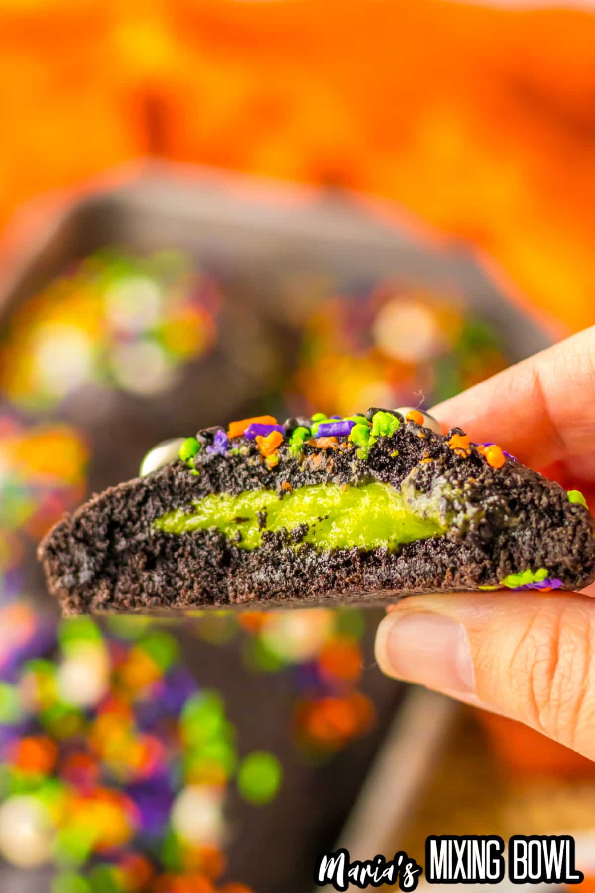 black velvet cookie held in a woman's hand to show the cream cheese inside.