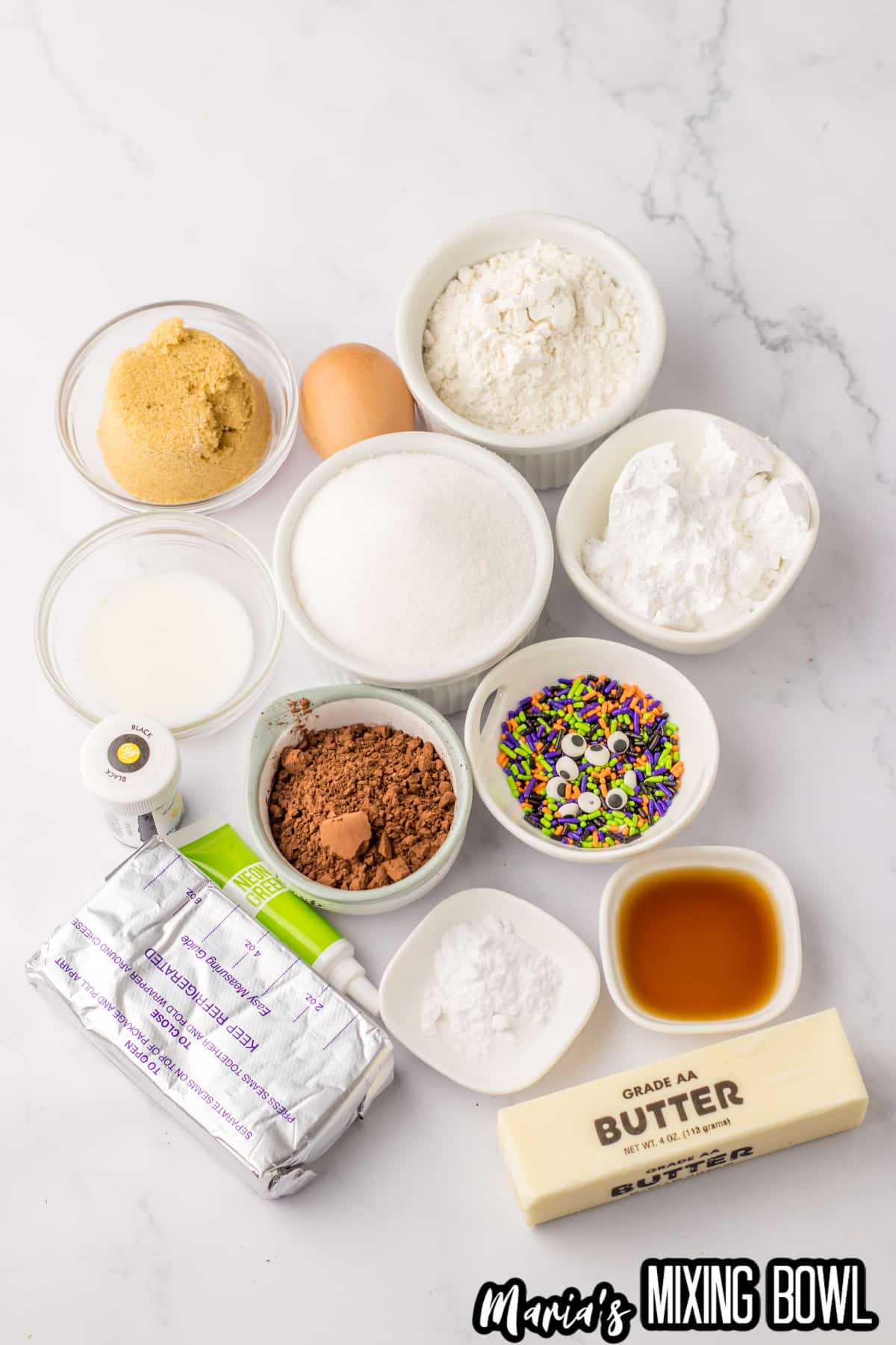 bowls of brown sugar, granulated sugar, powdered sugar, milk, cocoa powder, vanilla extract, butter, cream cheese, food coloring and sprinkles.