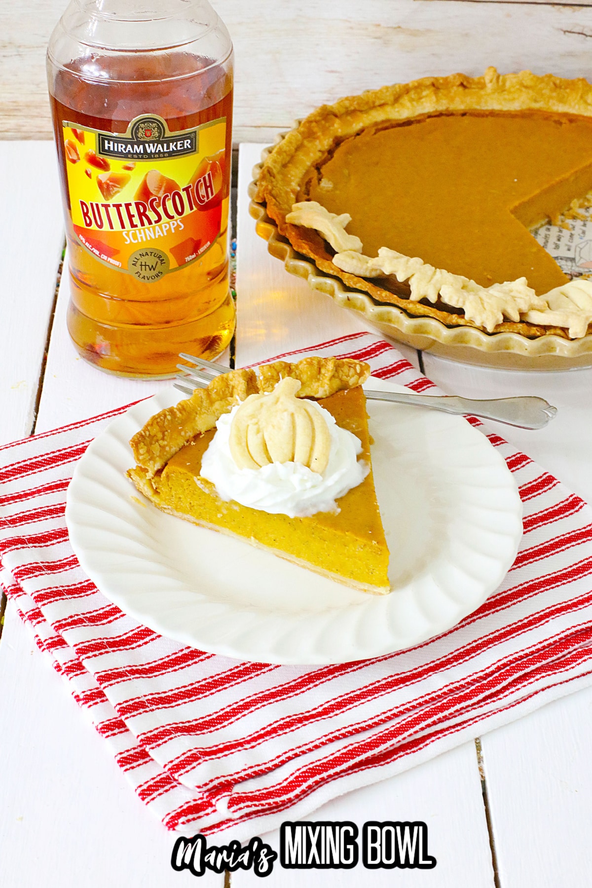 slice of boozy pumpkin pie topped with whipped cream on a plate.