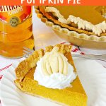 slice of boozy pumpkin pie topped with whipped cream on a plate.