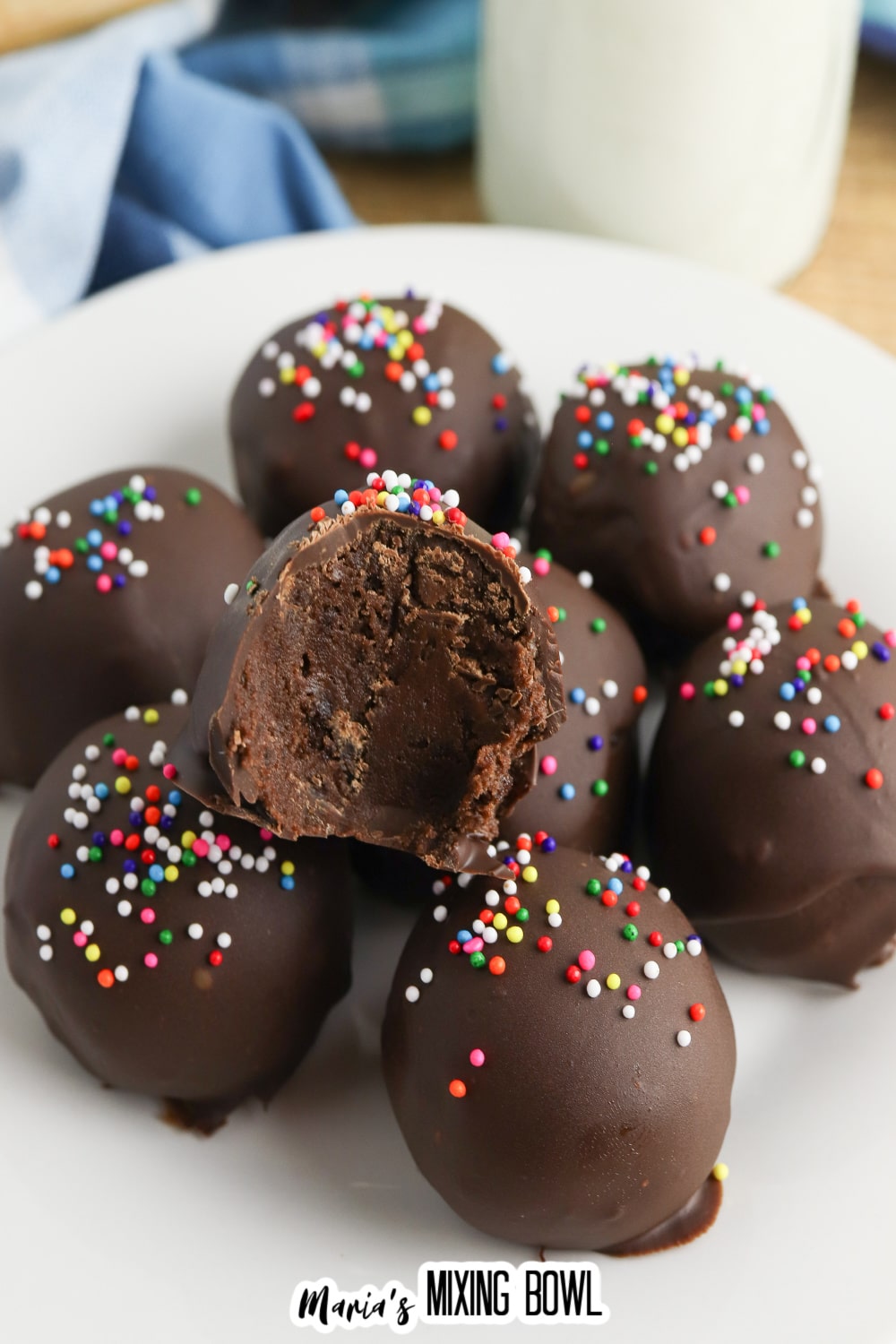 stack of brownie truffles on a white plate, the top one has a bite missing.