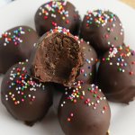 brownie truffles stacked on a plate with the top one missing a bite.