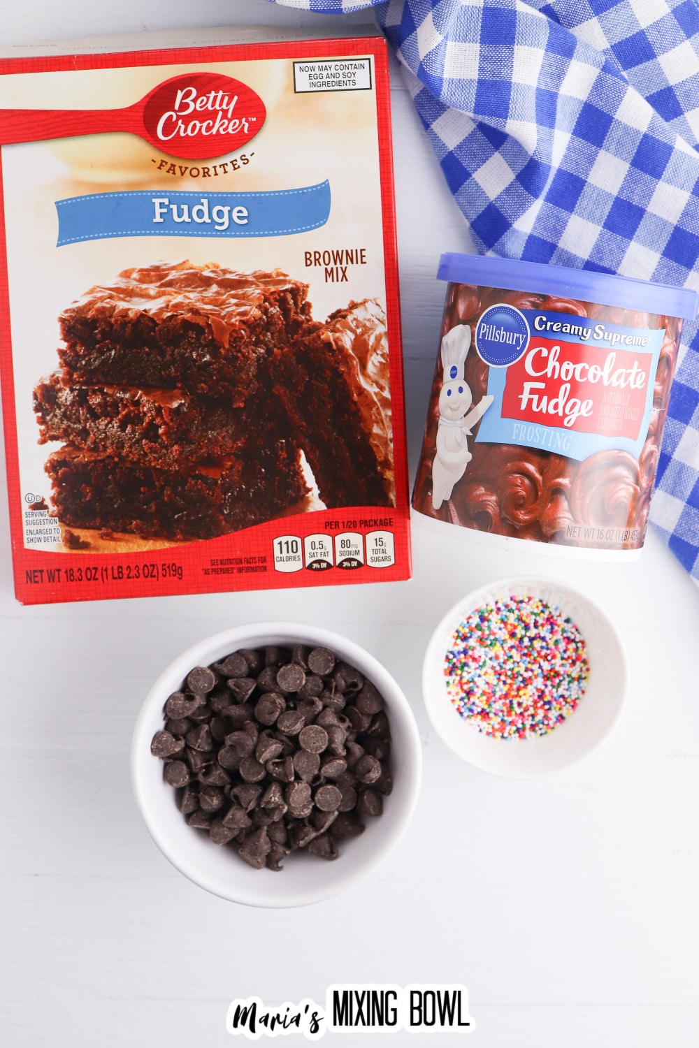 box of brownie mix, can of chocolate frostings, bowl of semi sweet chocolate chips, and bowl of sprinkles.