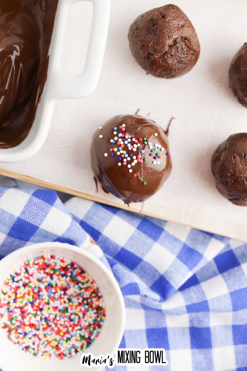 sprinkles being added to the top of freshly dipped brownie truffles.