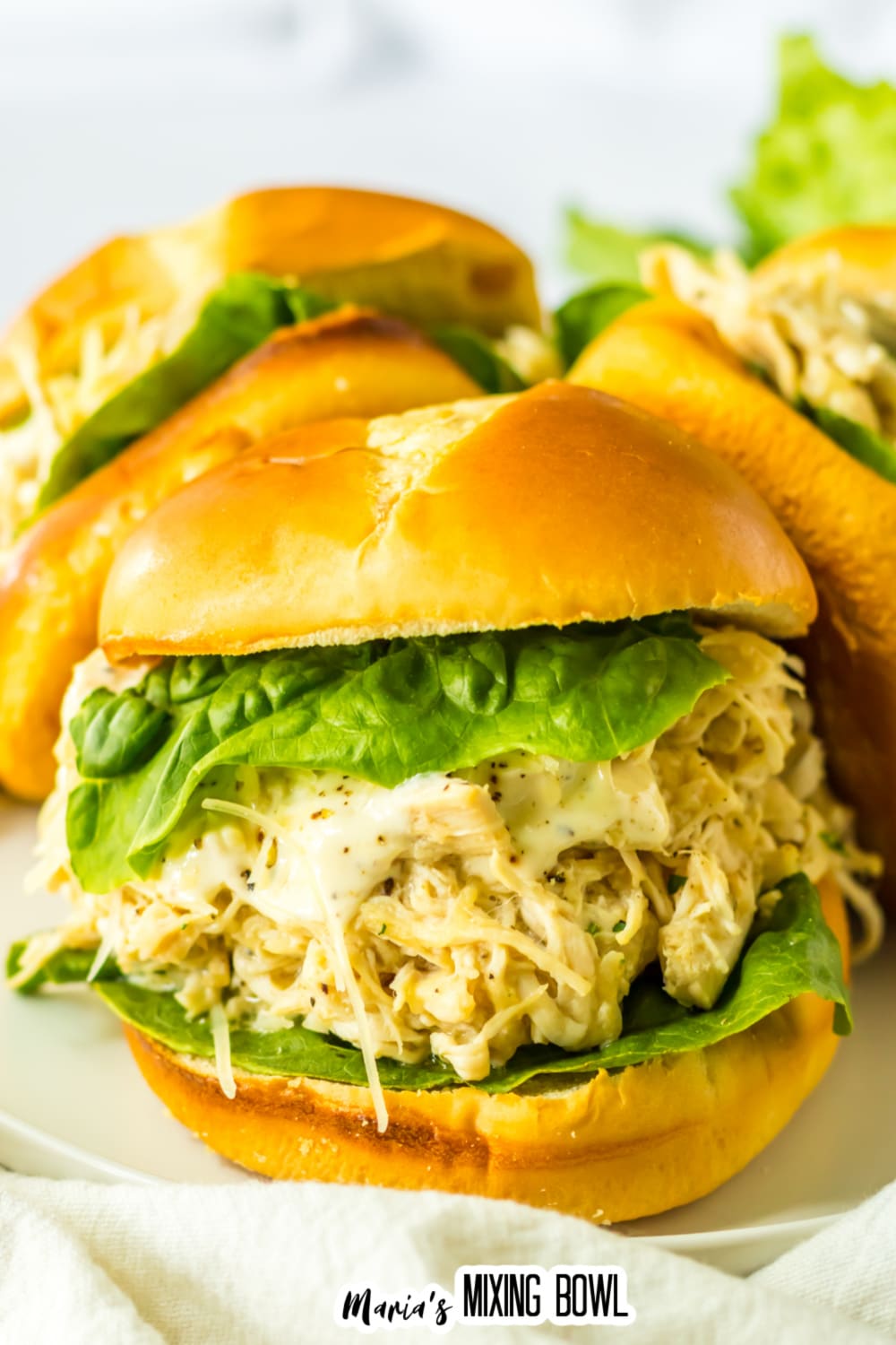 three chicken ceasar sandwiches on a white plate.