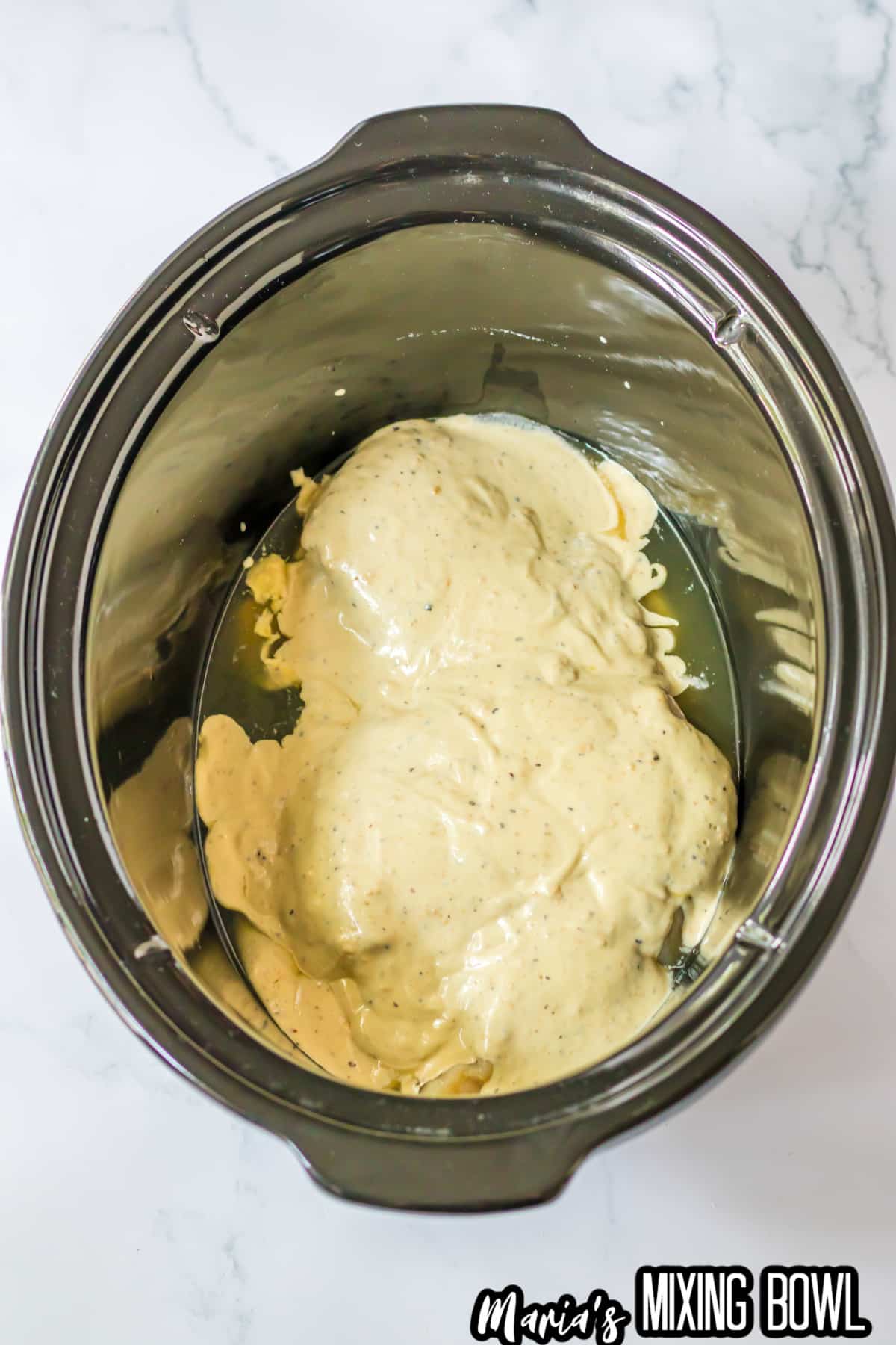 raw chicken breasts, chicken broth, and cesear dressing in a slow cooker.