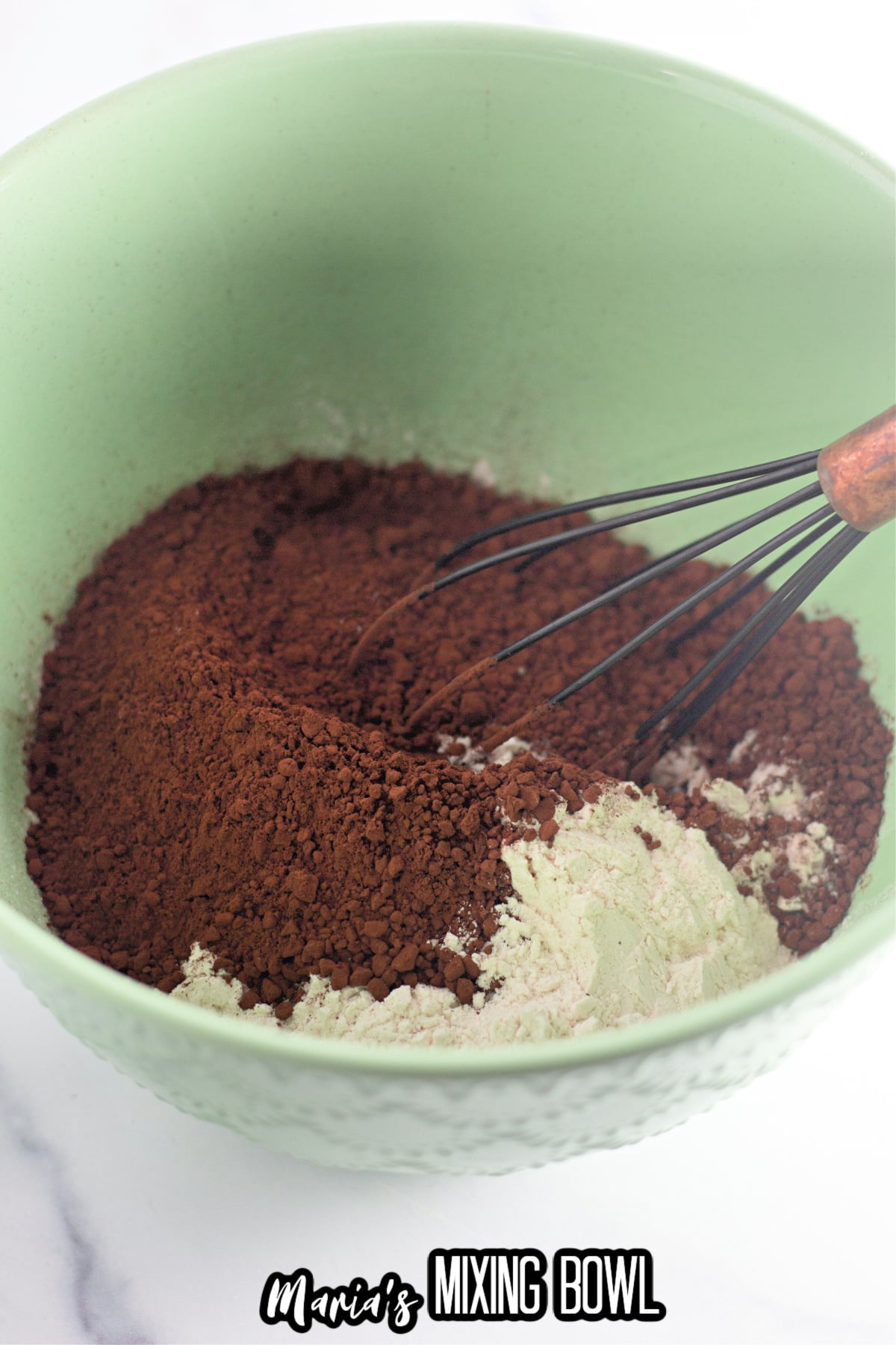 cocoa and flour being mixed together in a mixing bowl.