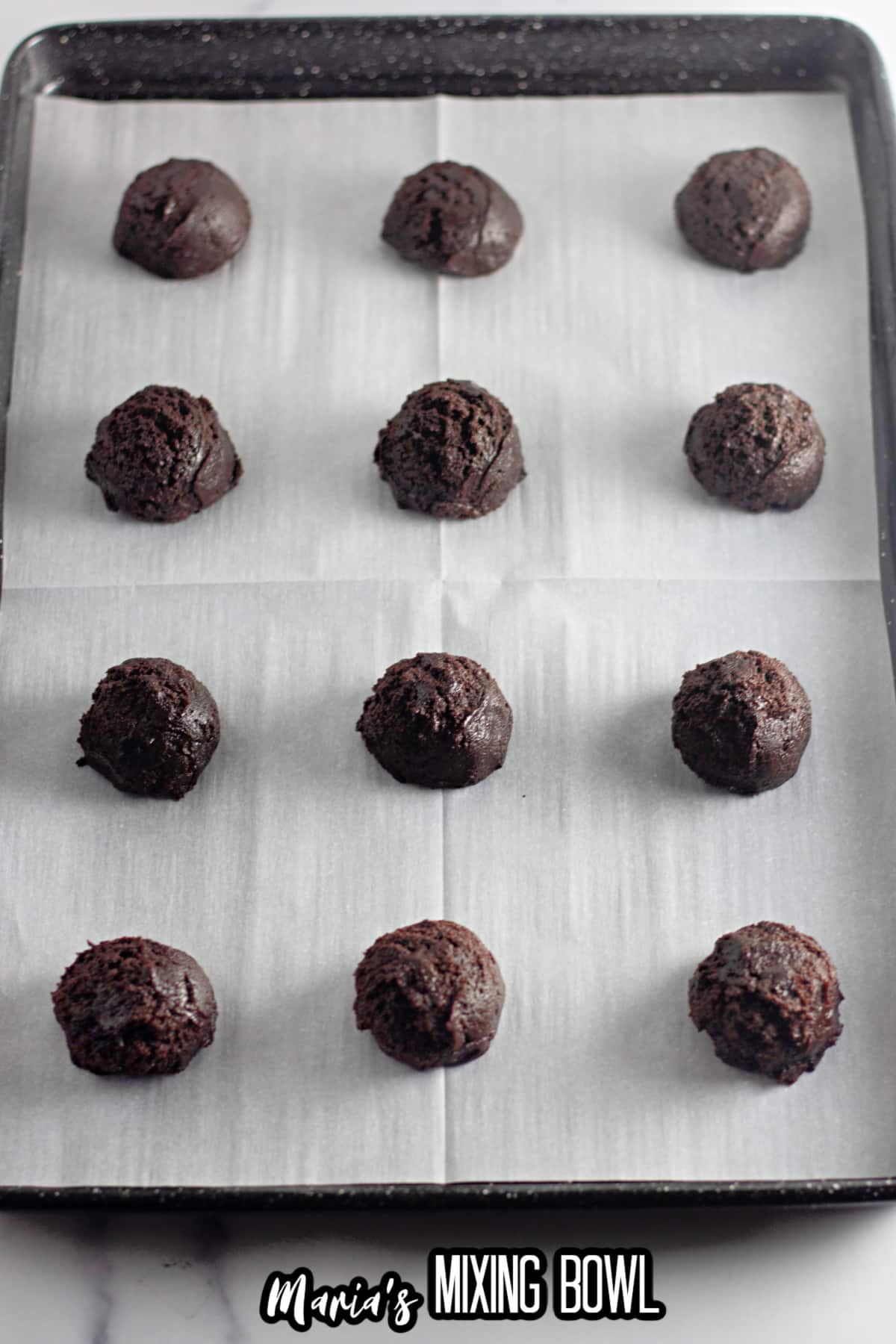 cookie dough balls on a parchment lined baking sheet.
