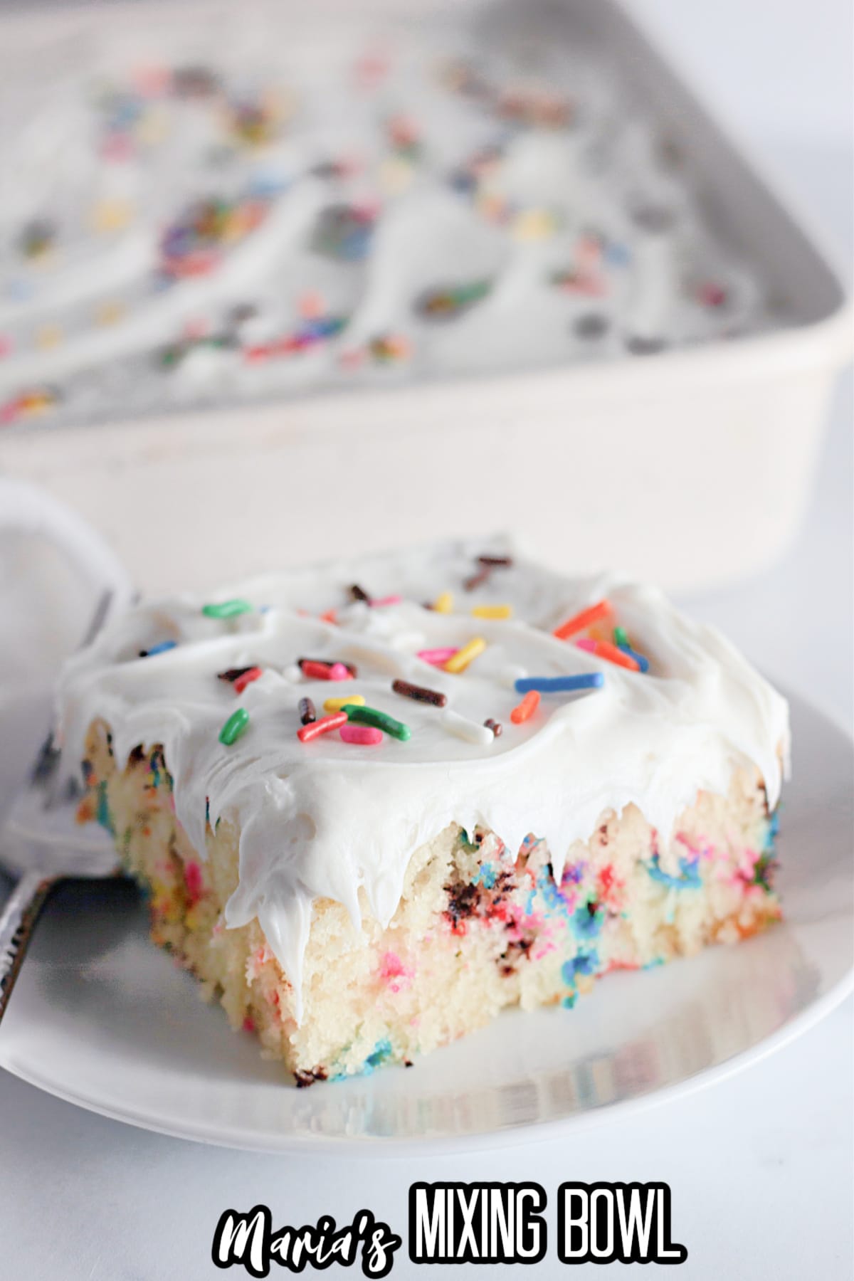 slice of funfetti cake on a white plate with a fork.