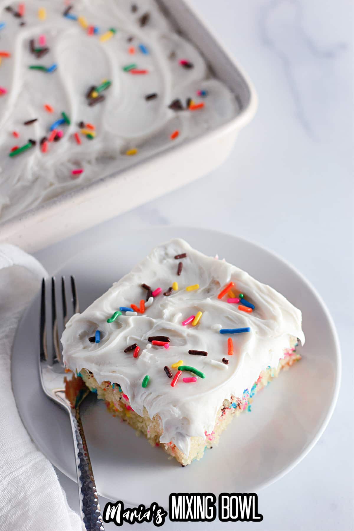 slice of funfetti cake on a white plate with a fork.