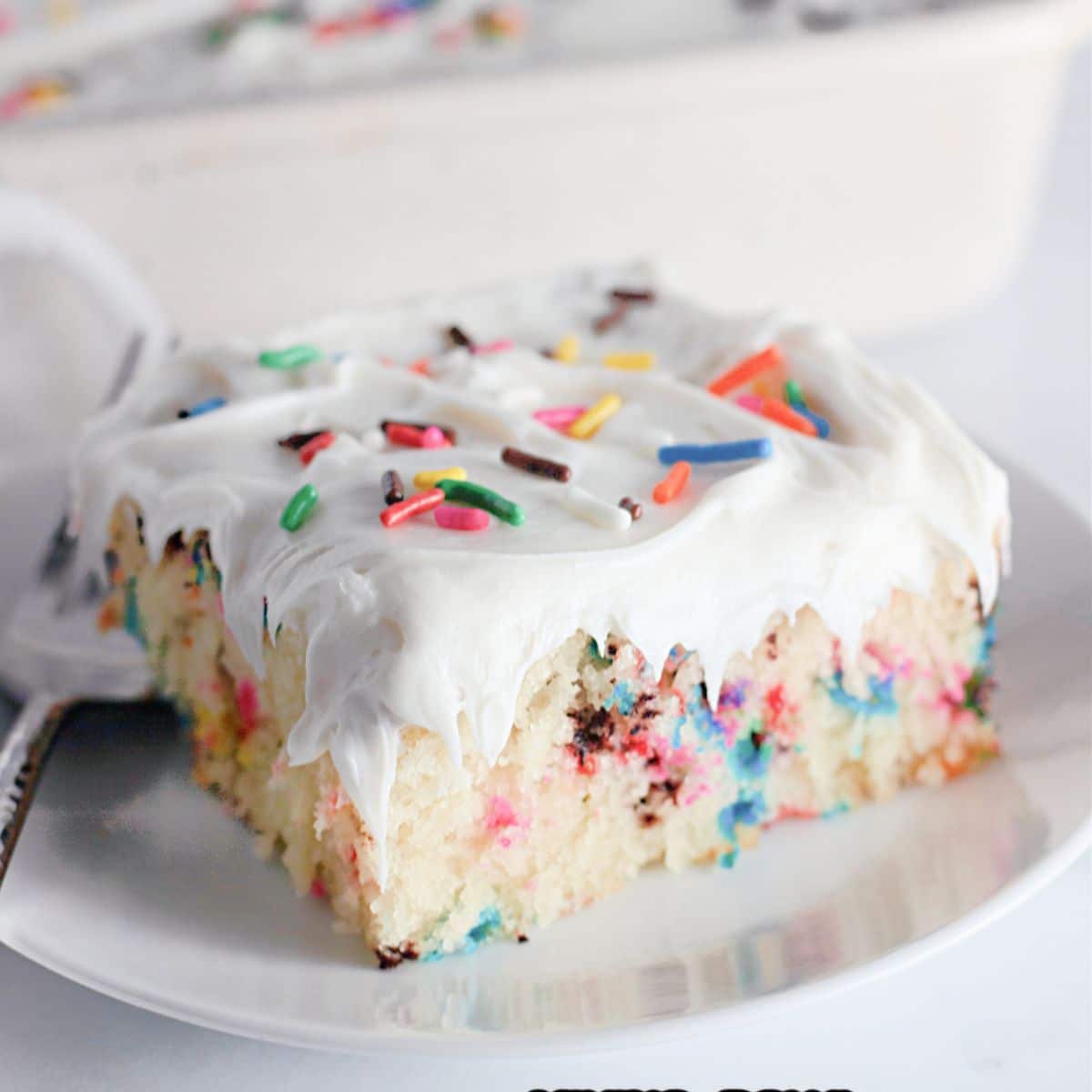 slice of funfetti cake on a white plate with a fork.