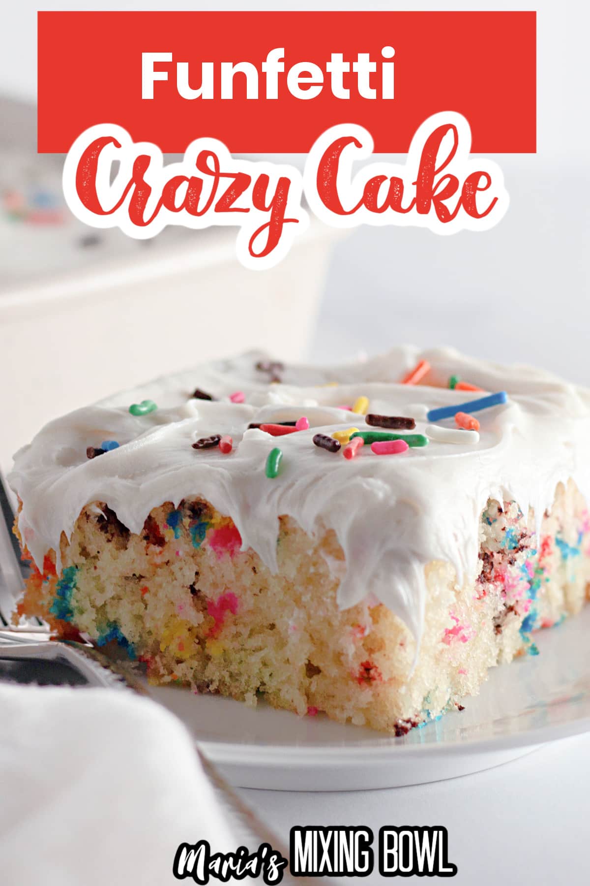 slice of funfetti cake on a white plate with a fork.
