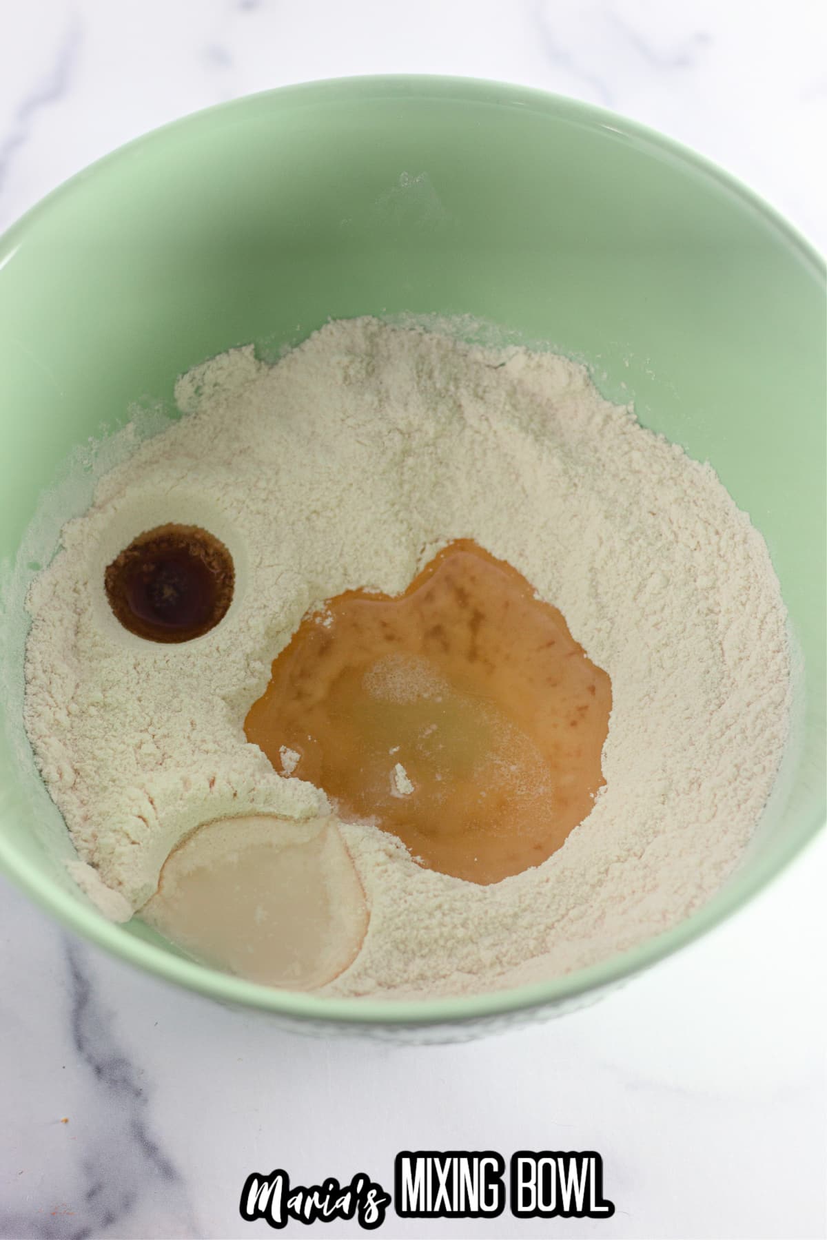 oil, vinegar, and vanilla extract being to the dry ingredients in a mixing bowl.