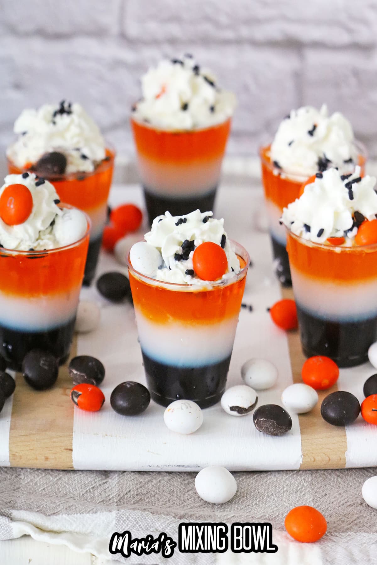 layered halloween shots on a wooden cutting board surrounded by M&M's.