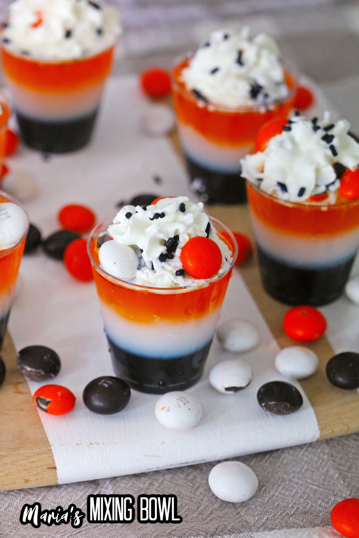 layered halloween shots on a wooden cutting board surrounded by M&M's.