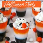 layered halloween shots on a wooden cutting board surrounded by M&M's.