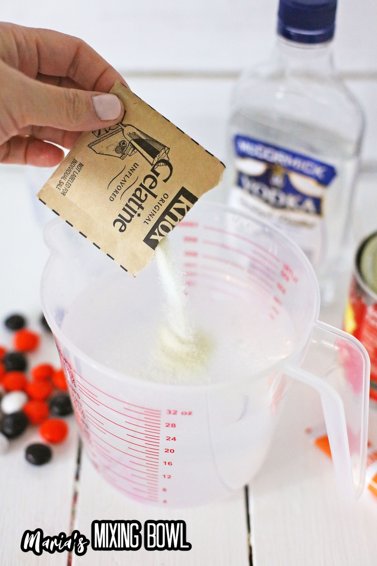 gelatin being added to water in a plastic measuring cup.