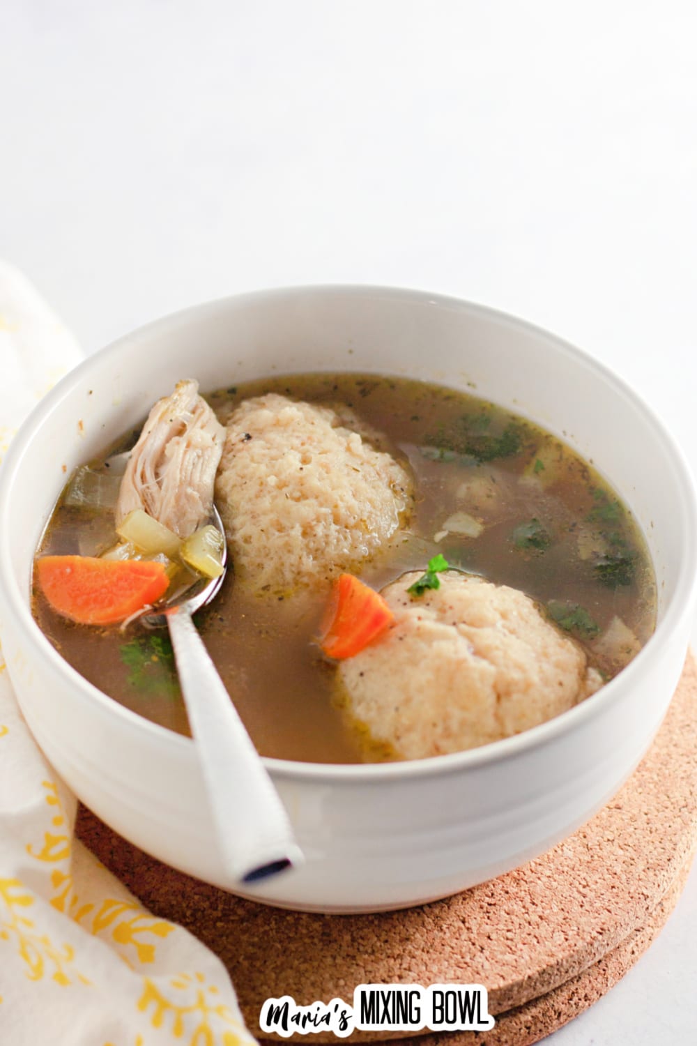 bowl of matzo ball soup with a spoon in it.