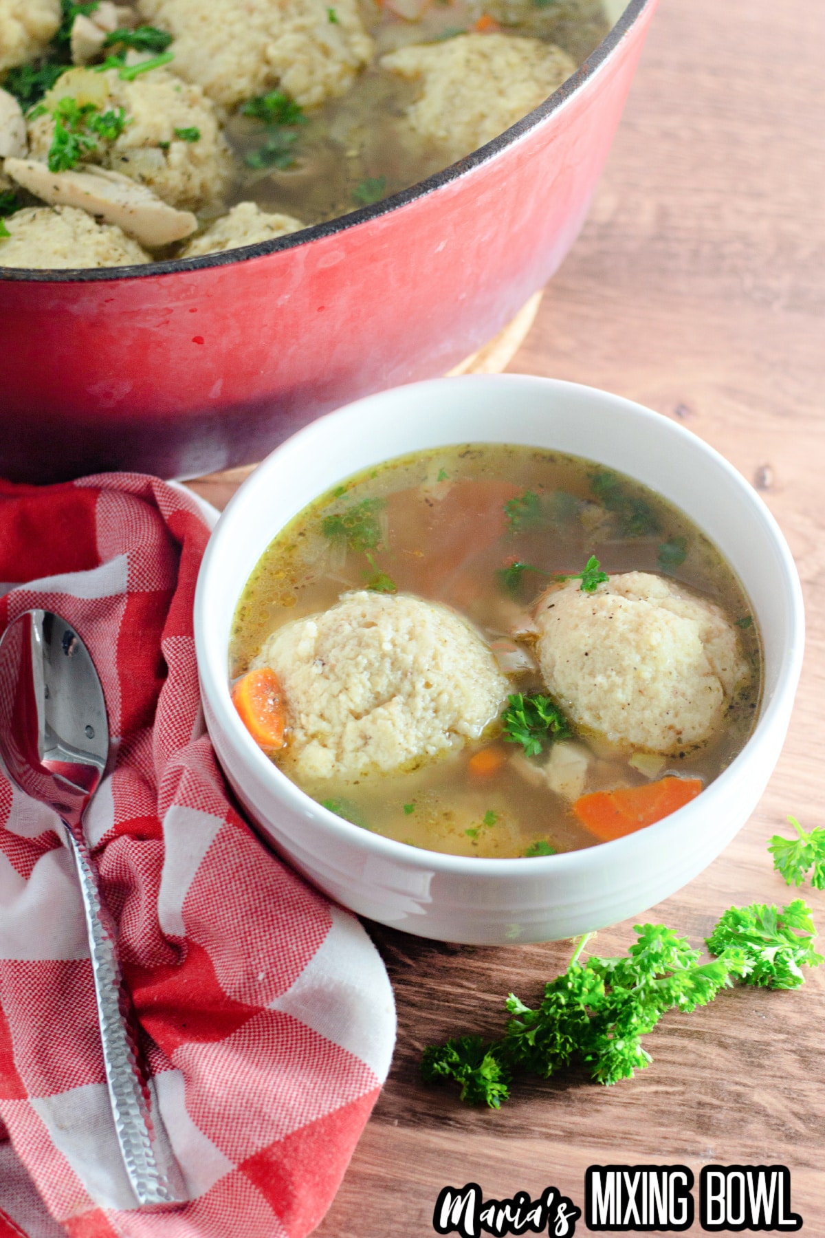 bowl filled with matzo ball soup that has been garnished with fresh parsley.