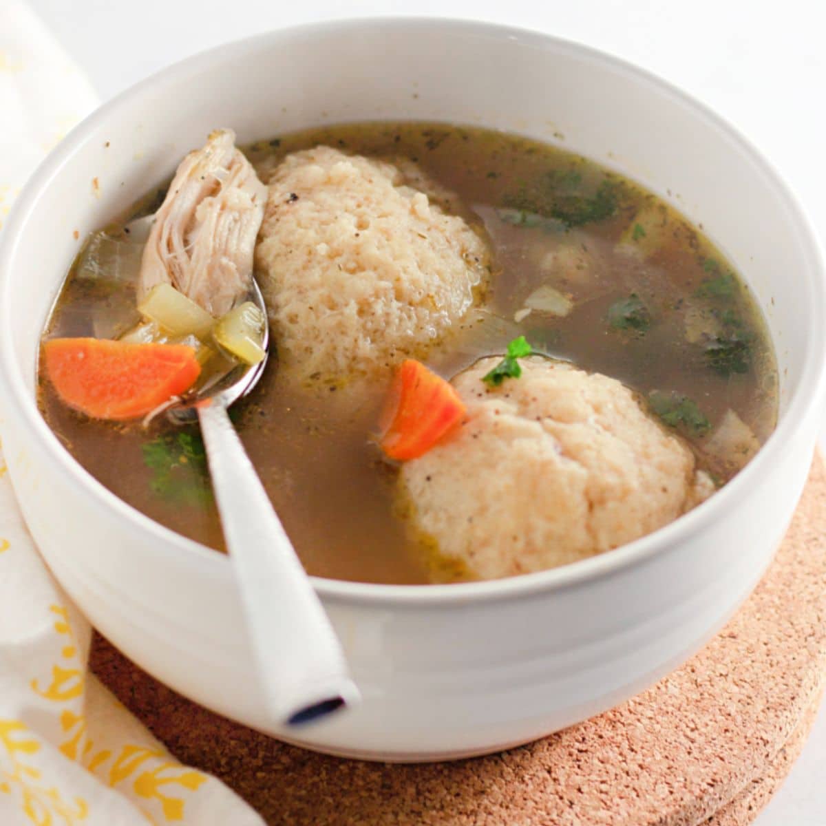 bowl of matzo ball soup with a spoon in it.