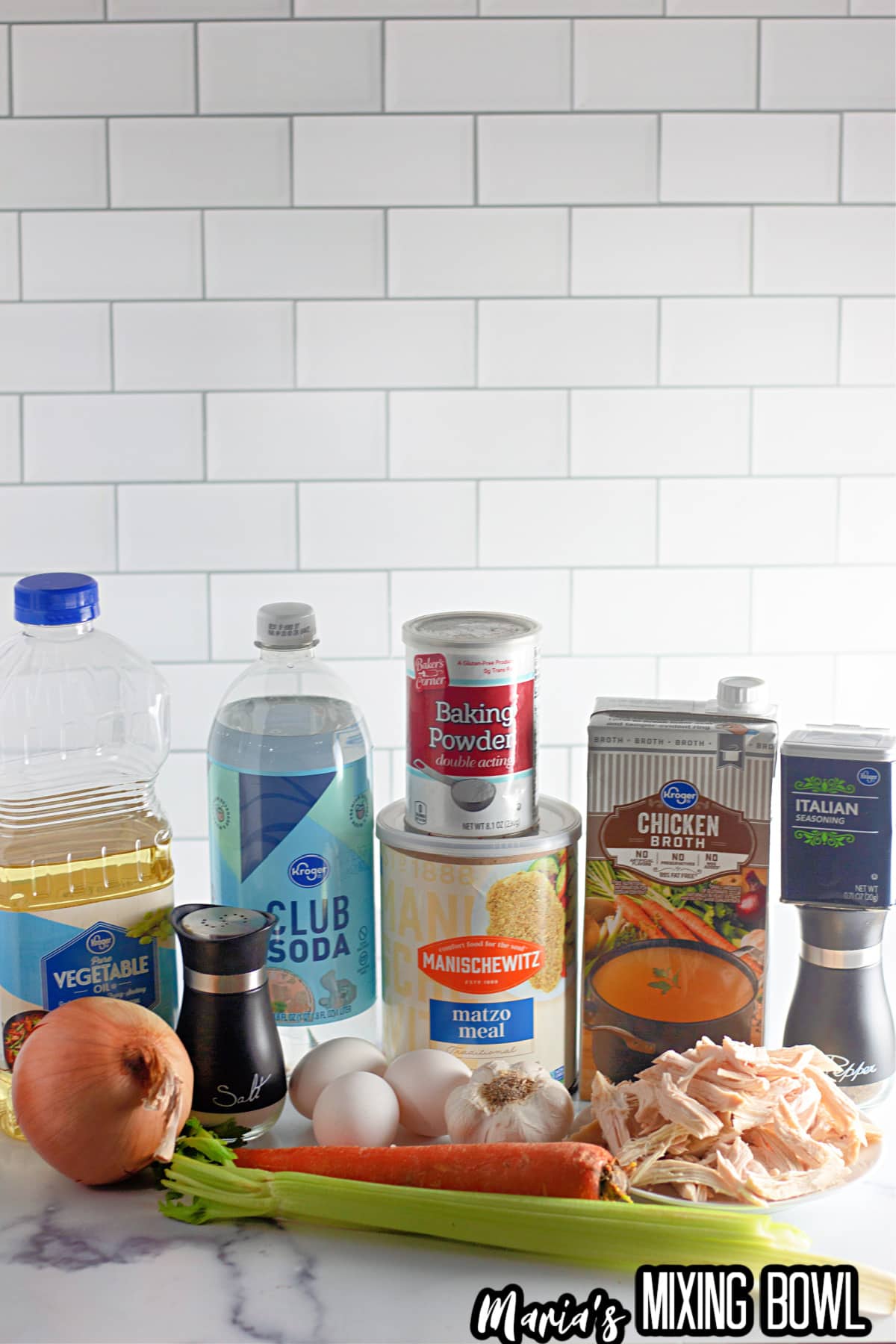 bottles of vegetable oil, club soda, baking powder, chicken broth, matzo meal, italian seasonings, pepper, salt, onions, eggs, garlic, shredded chicken, carrots, and celery.