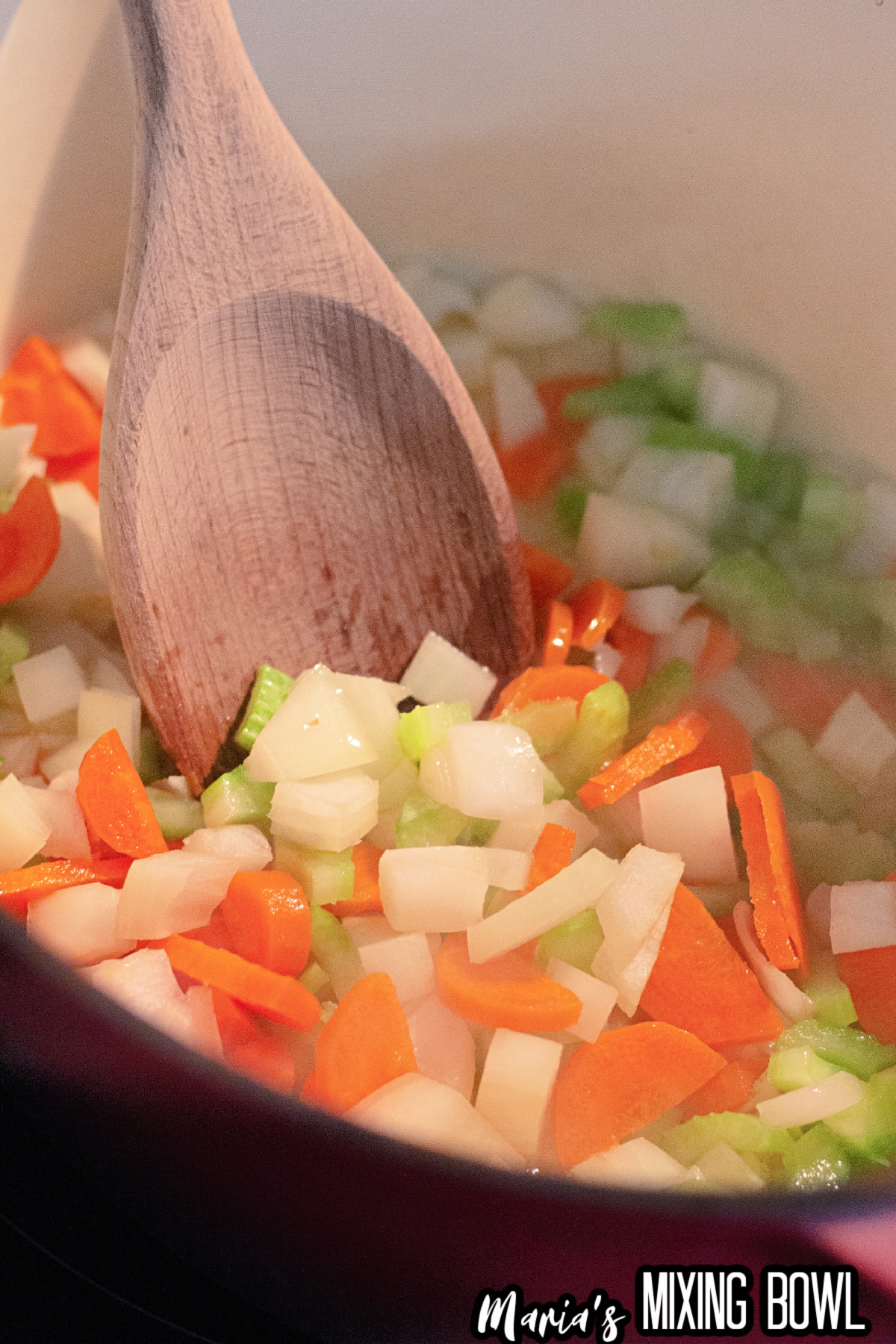 carrots, onions, and celery being saut&eacute;ed in a dutch oven.