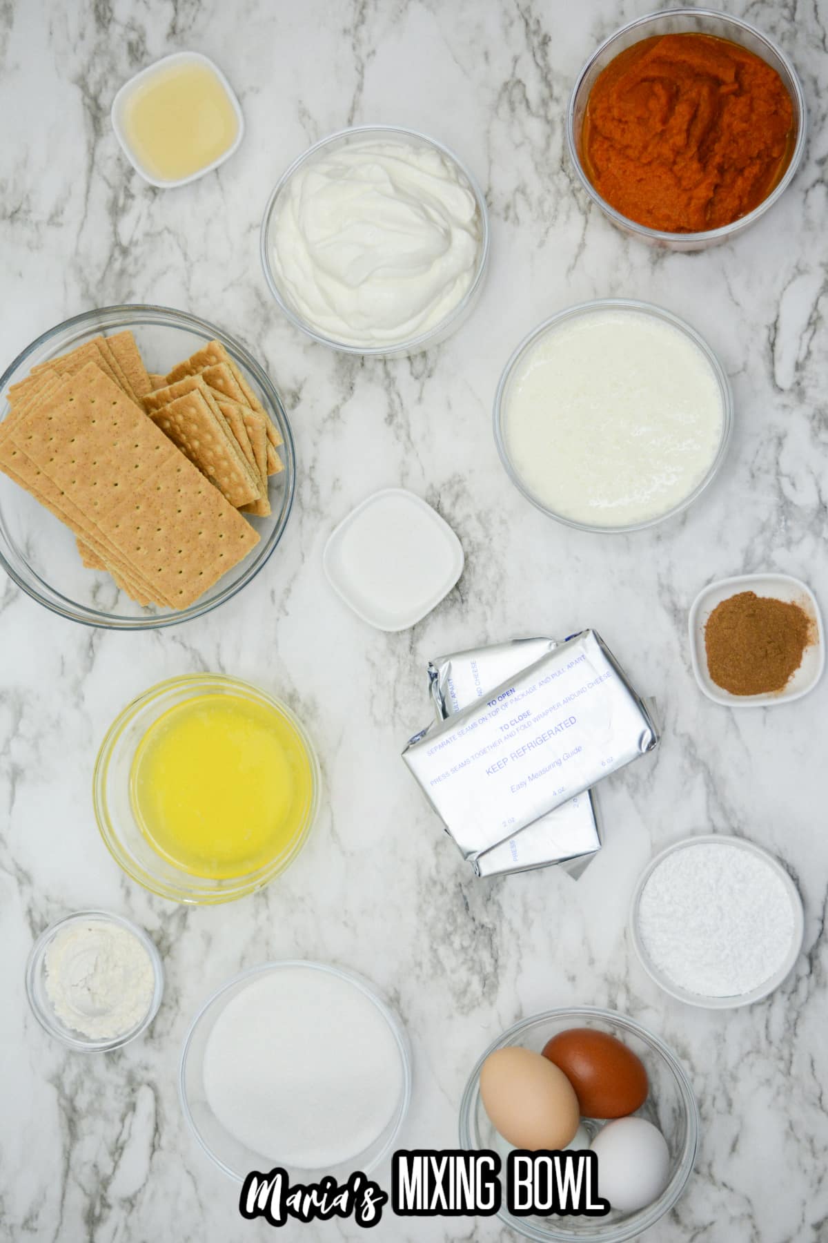 bowls of pumpkin puree, whipped cream, cream cheese, sugar, melted butter, eggs, pumpkin pie spice, and graham crackers.
