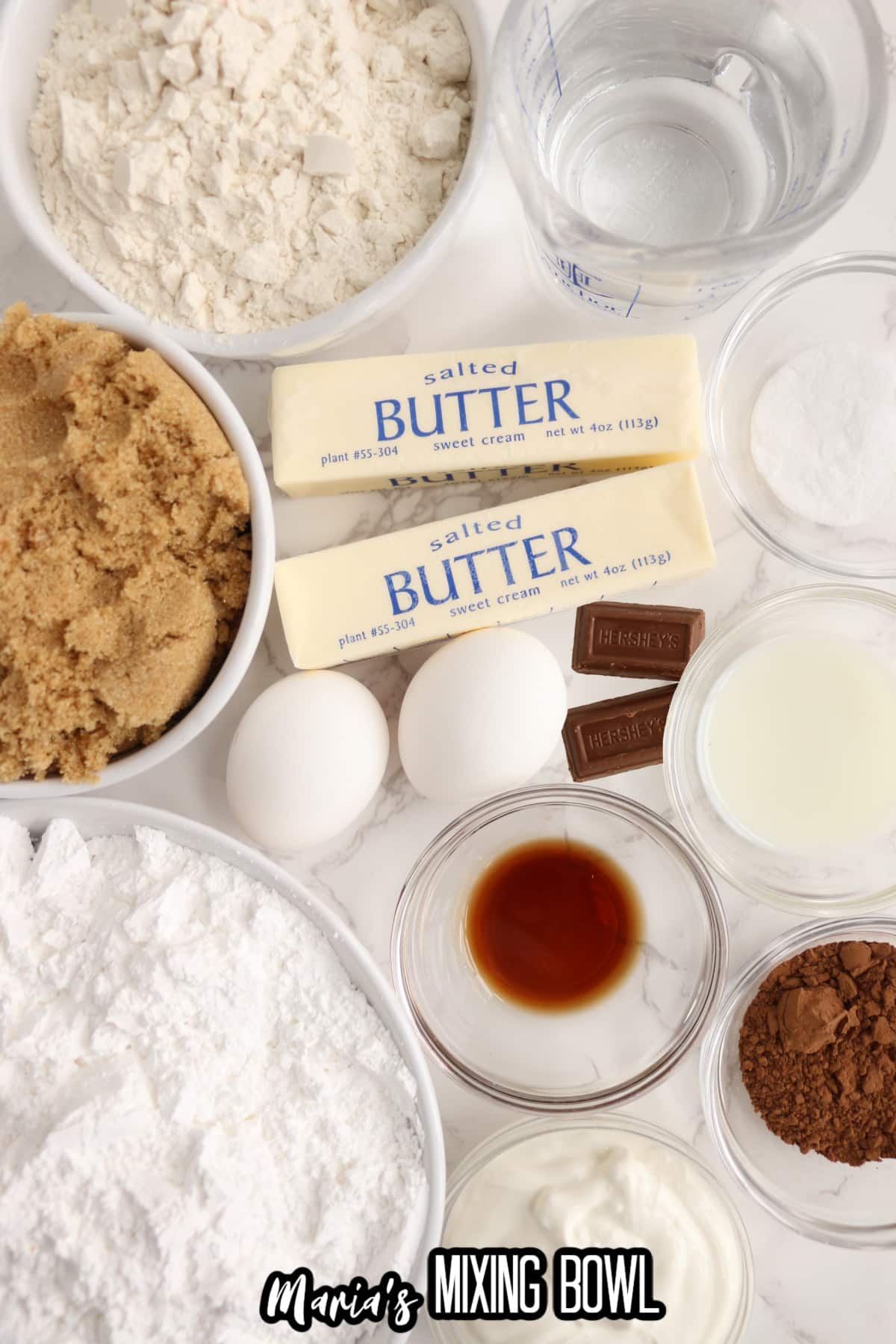 bowls of flour, brown sugar, water, butter, eggs, chocolate, vanilla, baking powder, cocoa powder, sour cream, heavy cream and powered sugar.