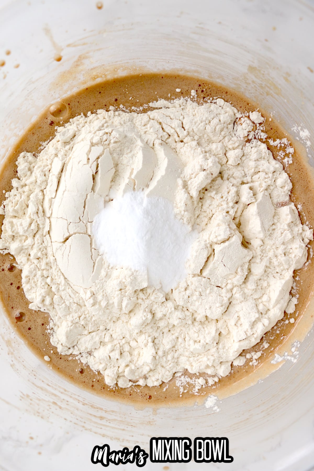 flour and salt being added to a bowl of wet ingredients.