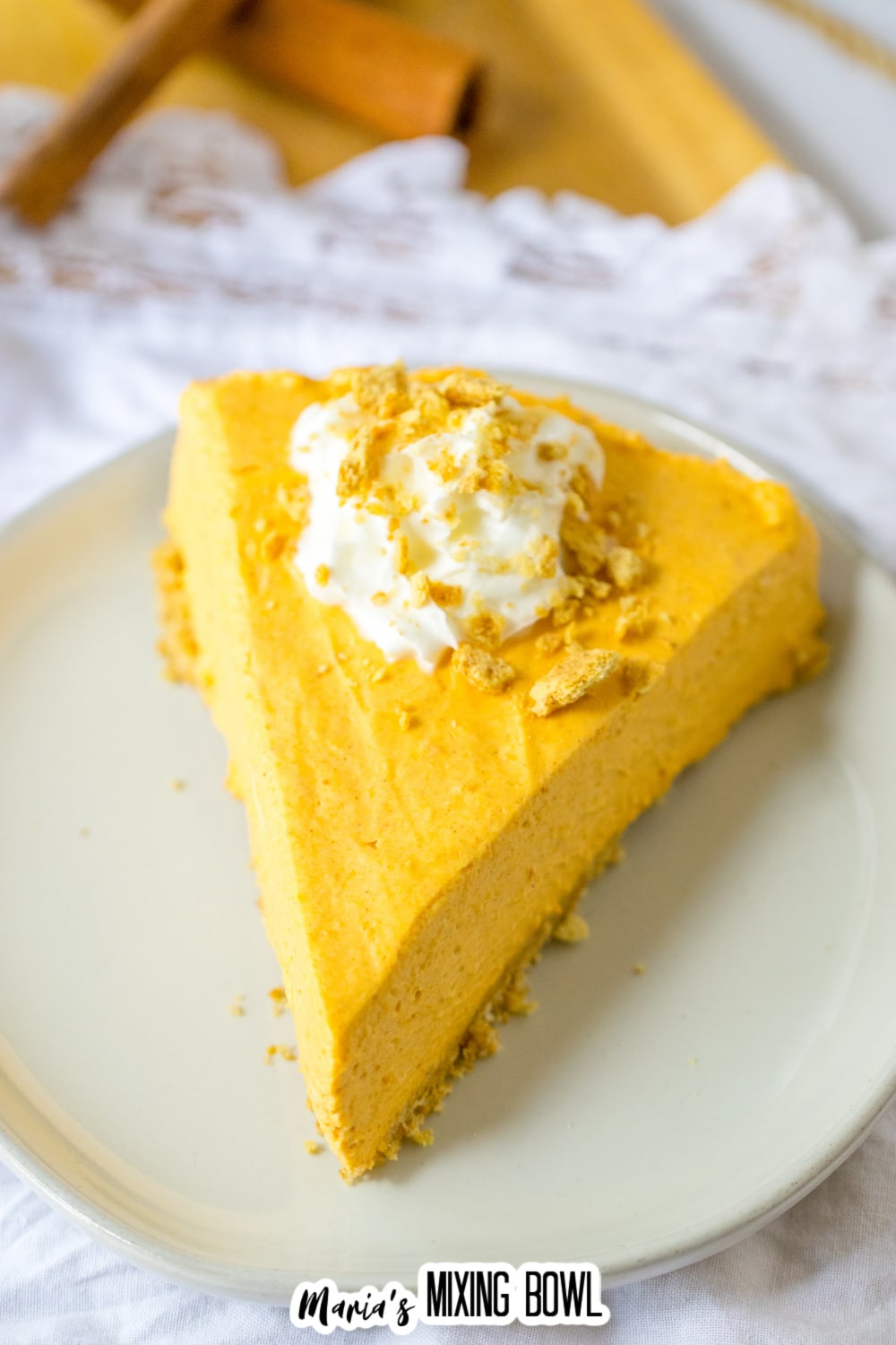 slice of pumpkin cheesecake topped with whipped cream on a plate.