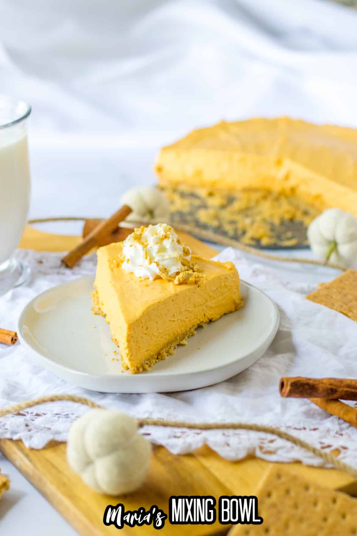 slice of pumpkin cheesecake topped with whipped cream on a plate.
