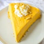 slice of pumpkin cheesecake topped with whipped cream on a plate.