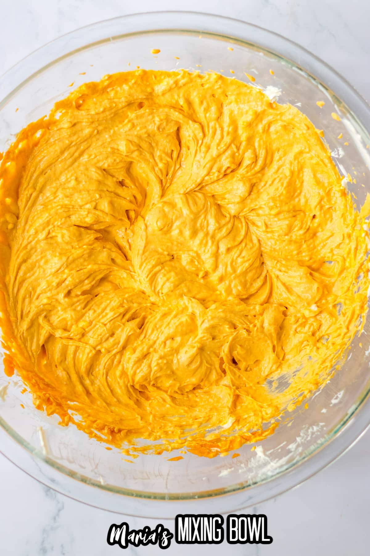 pumpkin cheesecake batter in a glass mixing bowl.