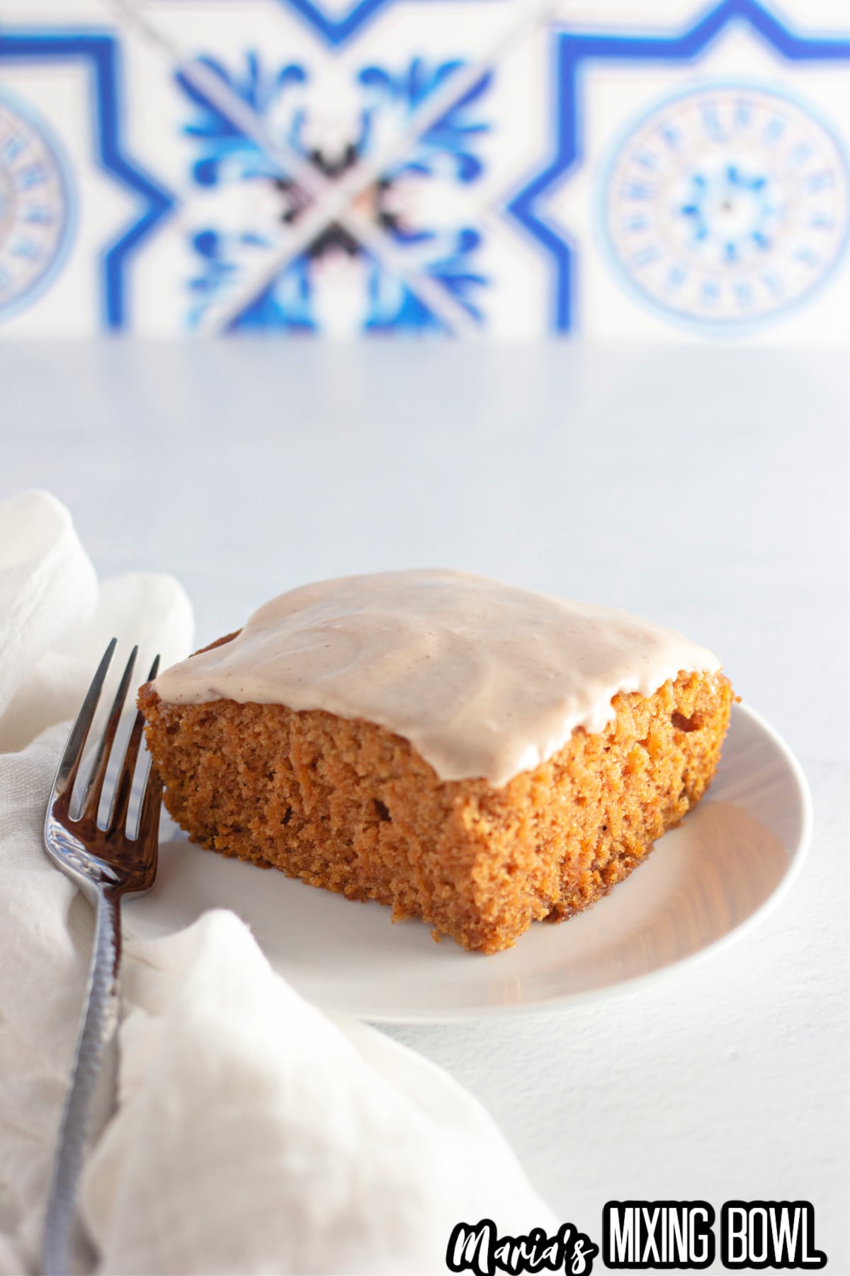 slice of pumpkin crazy cake topped with cream cheese frosting on a white plate.