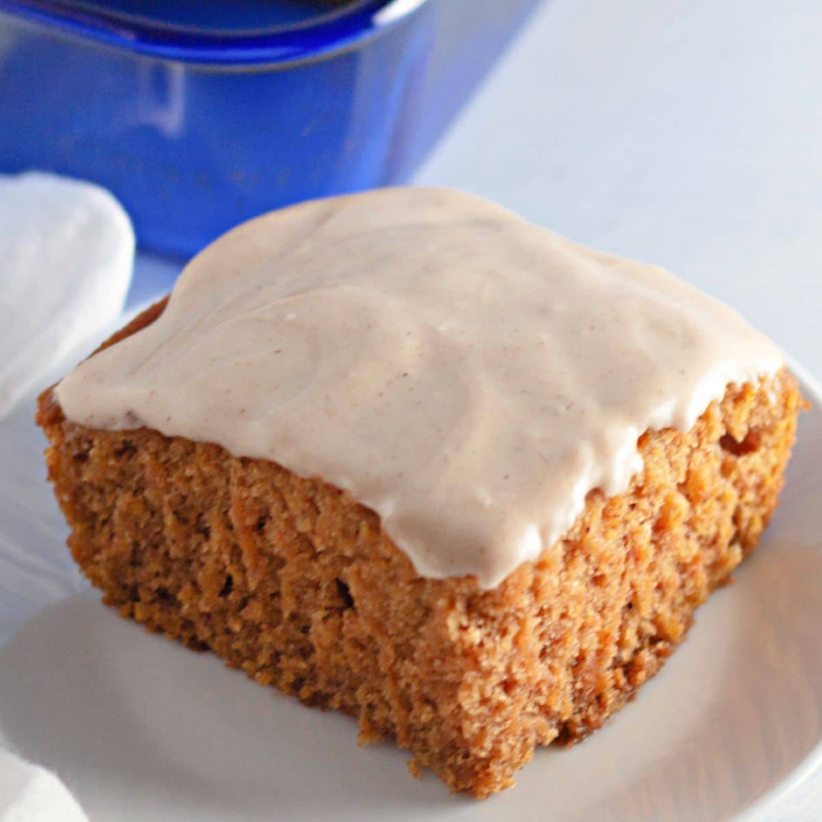 slice of pumpkin crazy cake topped with cream cheese frosting on a white plate.