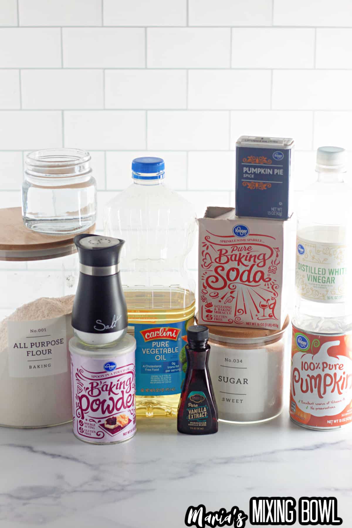 flour, water, baking powder, salt, vegetable oil, pumpkin pie spice, vanilla extract, baking soda, sugar, white vinegar, and pumpkin puree laid out.