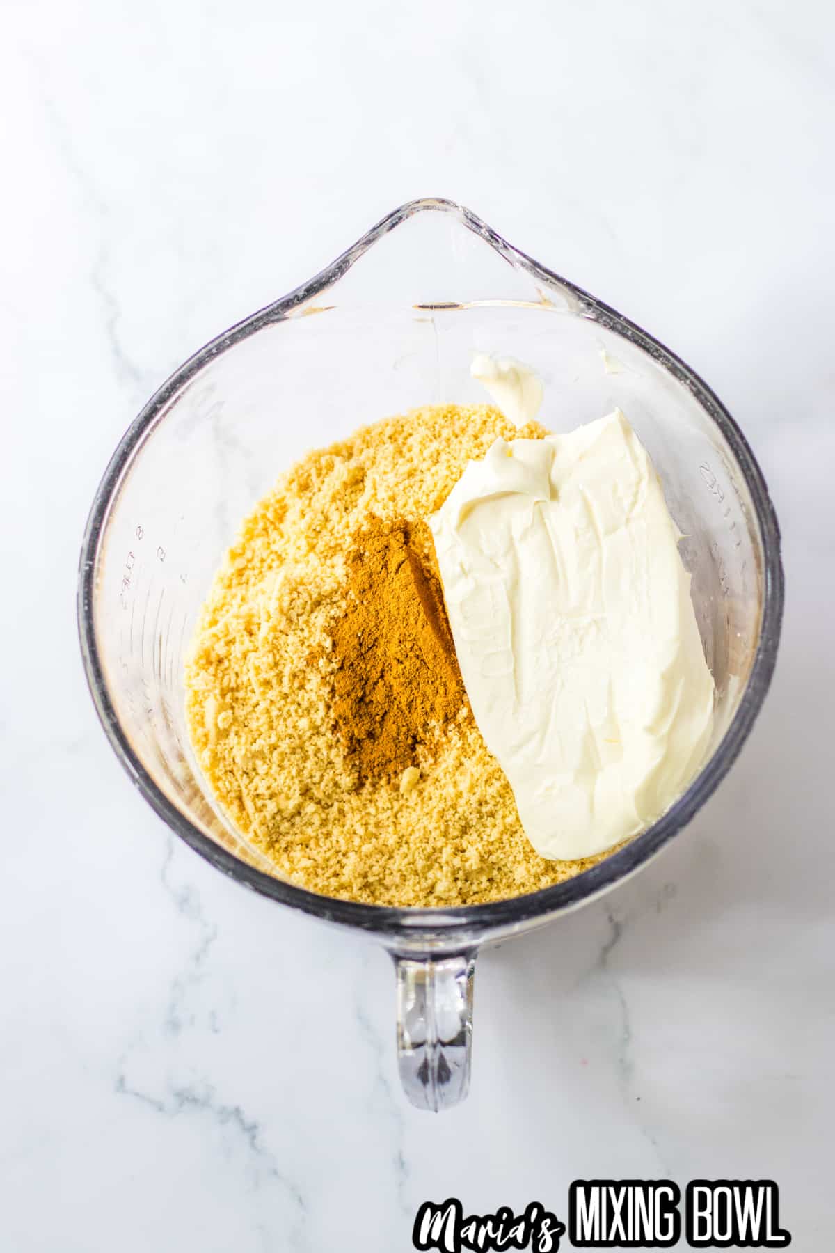 golden oreo cookies crushed, cream cheese block, and pumpkin pie spice in a glass mixing bowl.