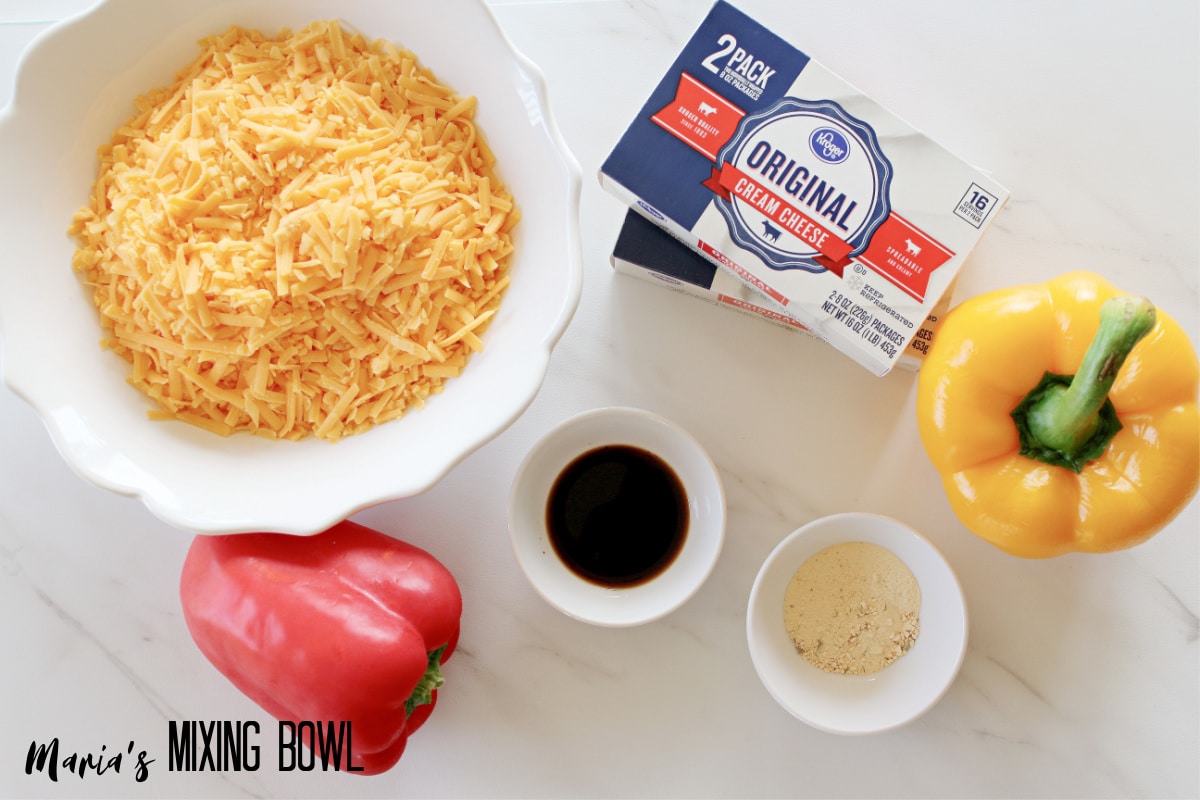bowls of shredded cheese, Worcestershire sauce, ranch seasoning mix, two blocks of cream cheese, and a yellow and red bell pepper.